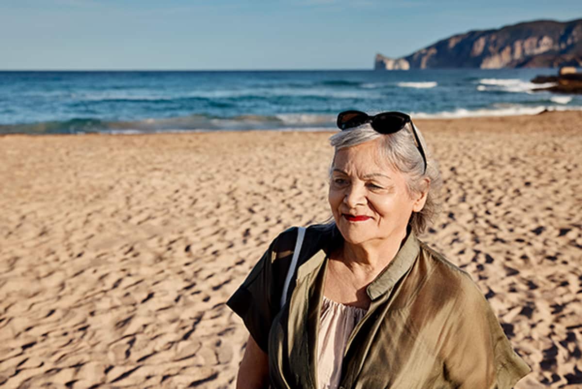 Frau am Strand mit Sonnenbrille auf Kopf